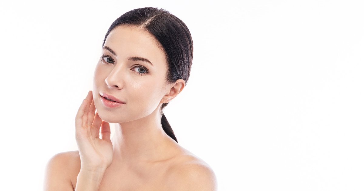 A woman with flawless, glowing skin gently touching her face, showcasing the radiant results of Skinvive treatment in Portsmouth, NH.