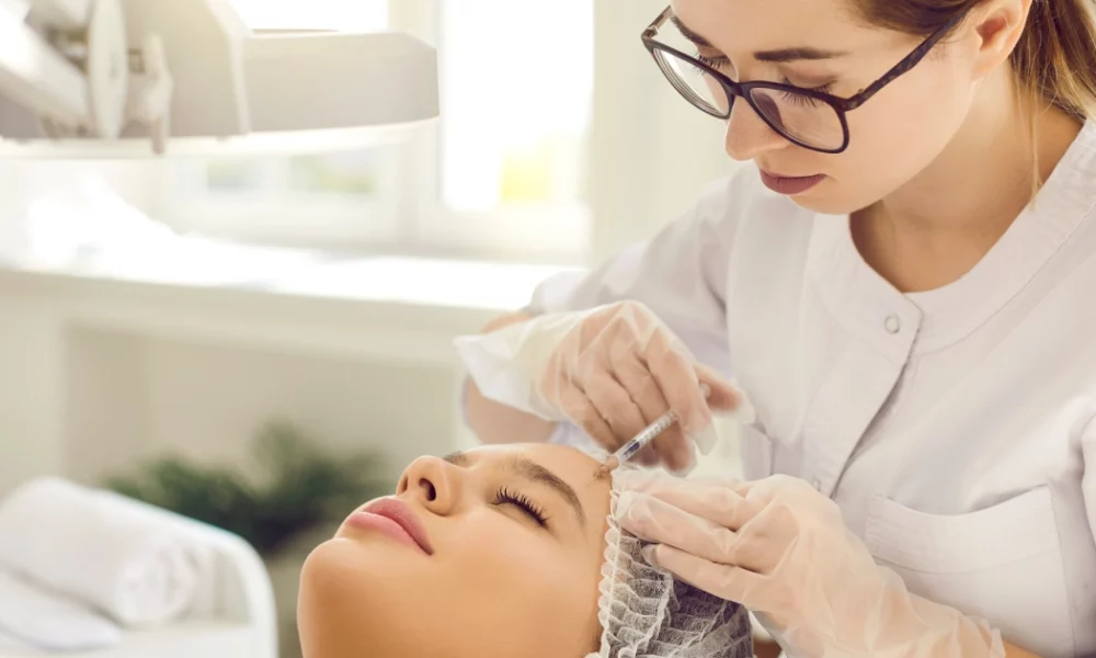 Woman receiving a Sculptra cosmetic injection in Portsmouth, NH, from a clinician in a bright medical setting.